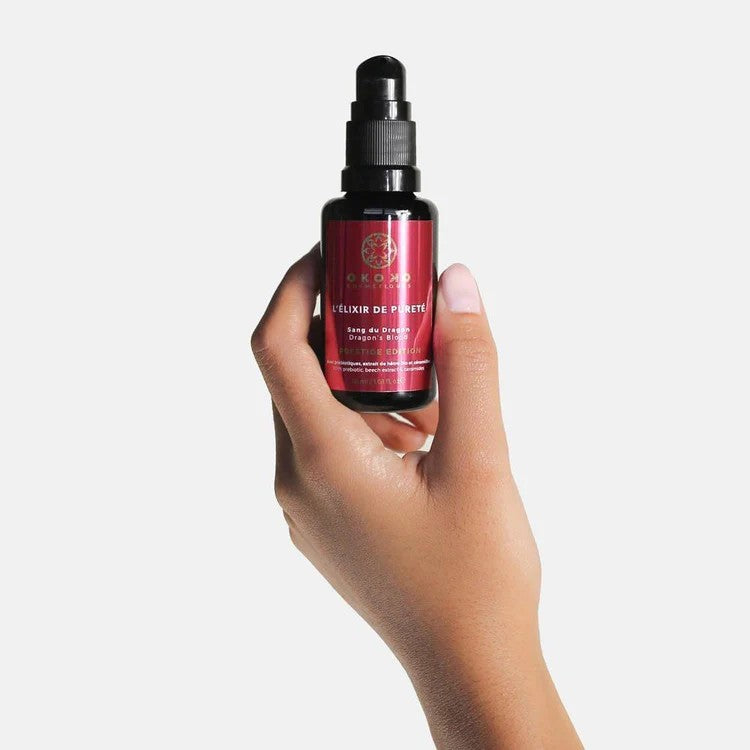 Hand holding OKOKO L’Élixir de Pureté Dragon’s Blood and Niacinamide serum — a luxury brightening and antioxidant skincare formula by Oyéta Kokoroko.