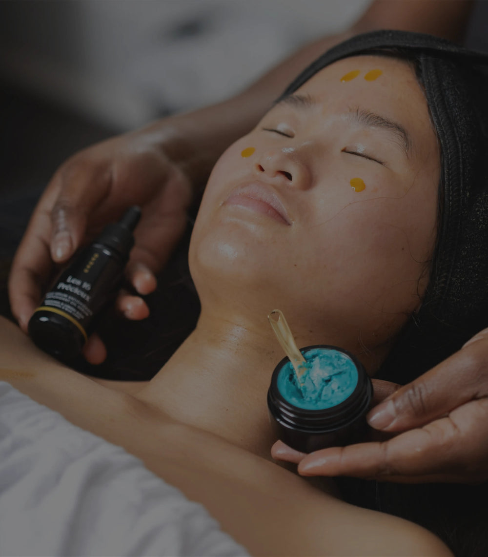 A Maison OKOKO facial ritual showing OKOKO Les 16 Précieux serum and Diamant Bleu cream with niacinamide being applied by a professional on glowing skin.
