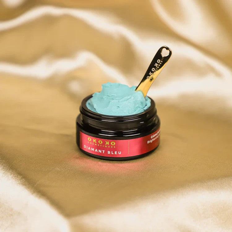 OKOKO Diamant Bleu brightening cream mask with gold spatula on a satin background — a luxurious blue skincare treatment designed to hydrate and illuminate the skin